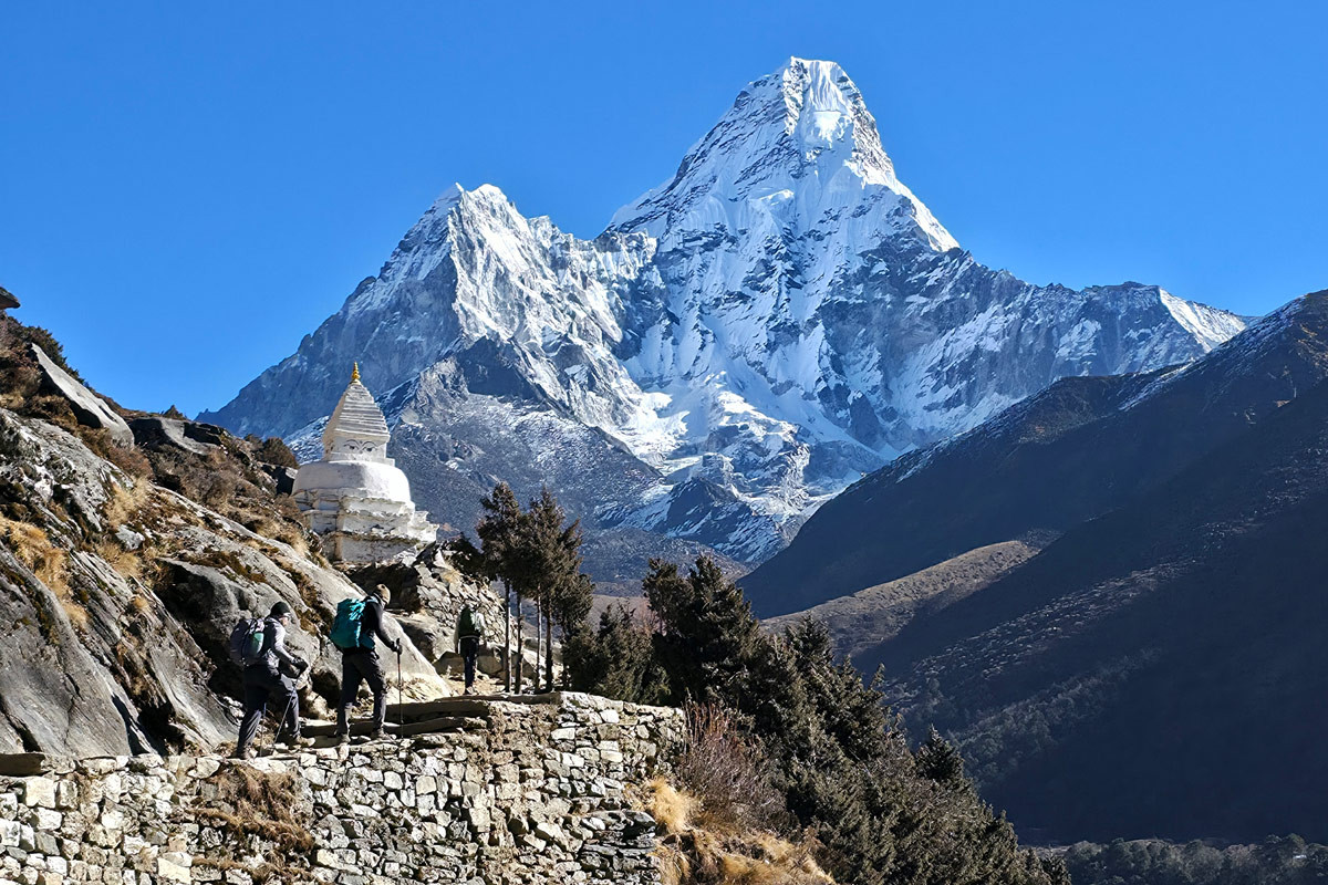a hiker jumping and posing in front of Everest Base Camp marker rock